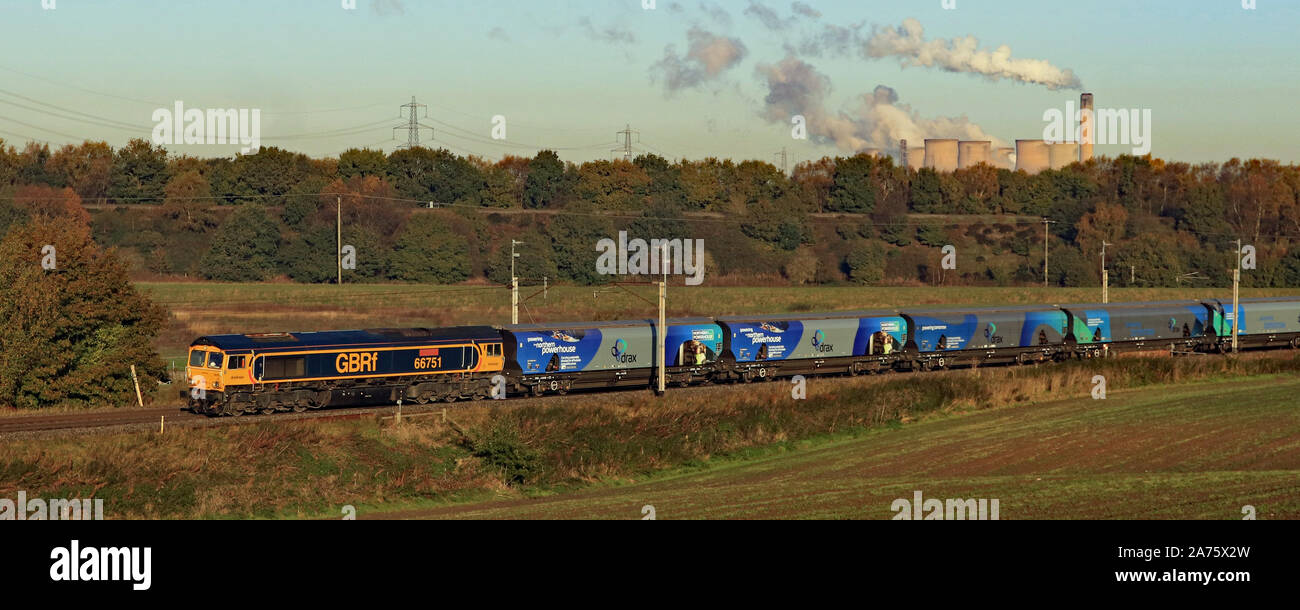 A GBRF diesel locomotive passes Daresbury near Runcorn on a bright autumn morning.  The train is carrying imported biomass to Drax power station. Stock Photo