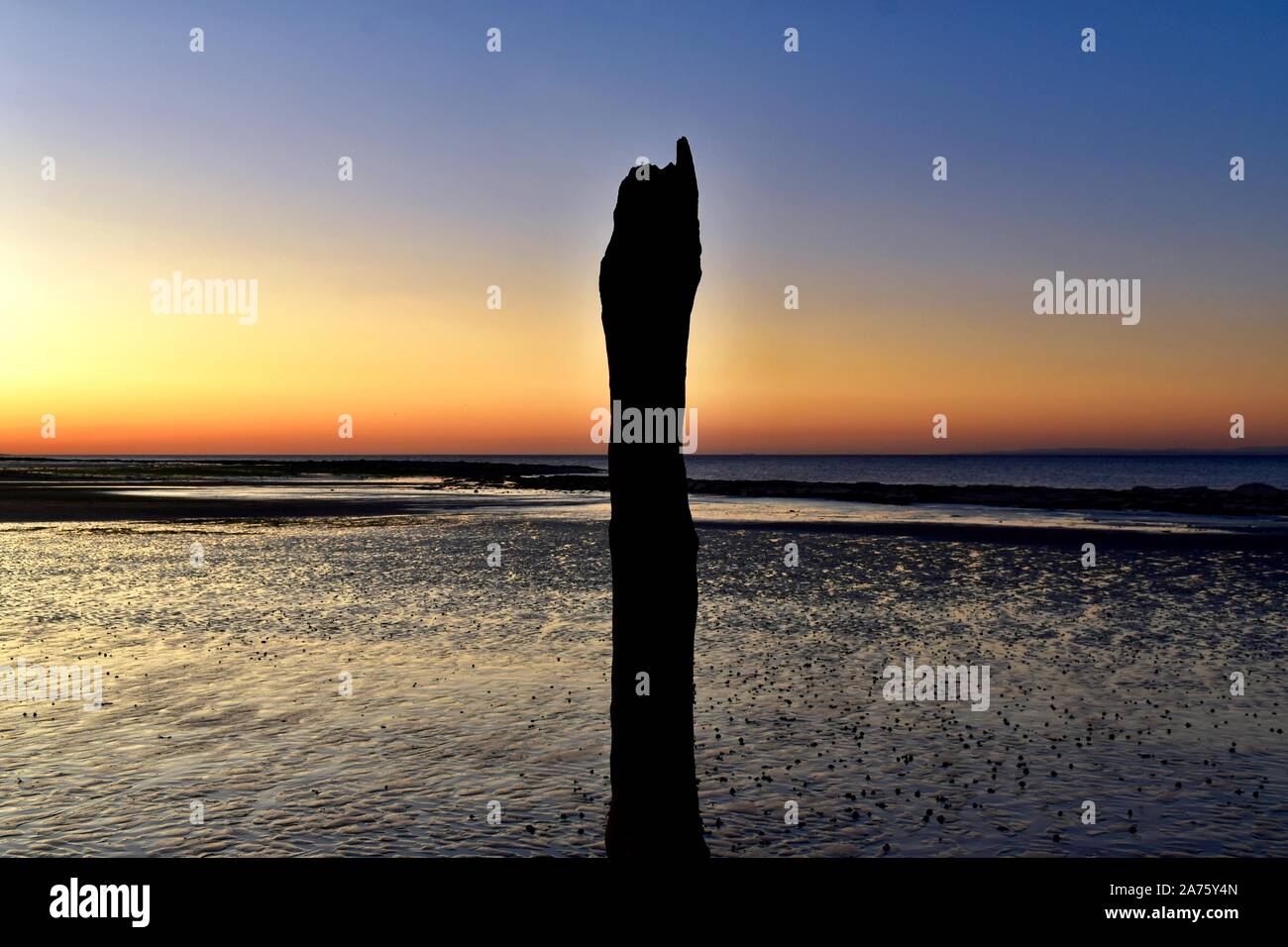 Old wooden post at sunset on Doniford beach. Stock Photo