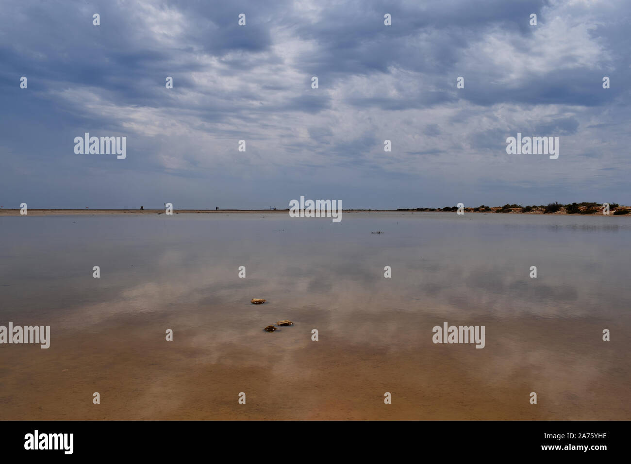 Cloudy sky reflected in the calm water of a lagoon Stock Photo - Alamy