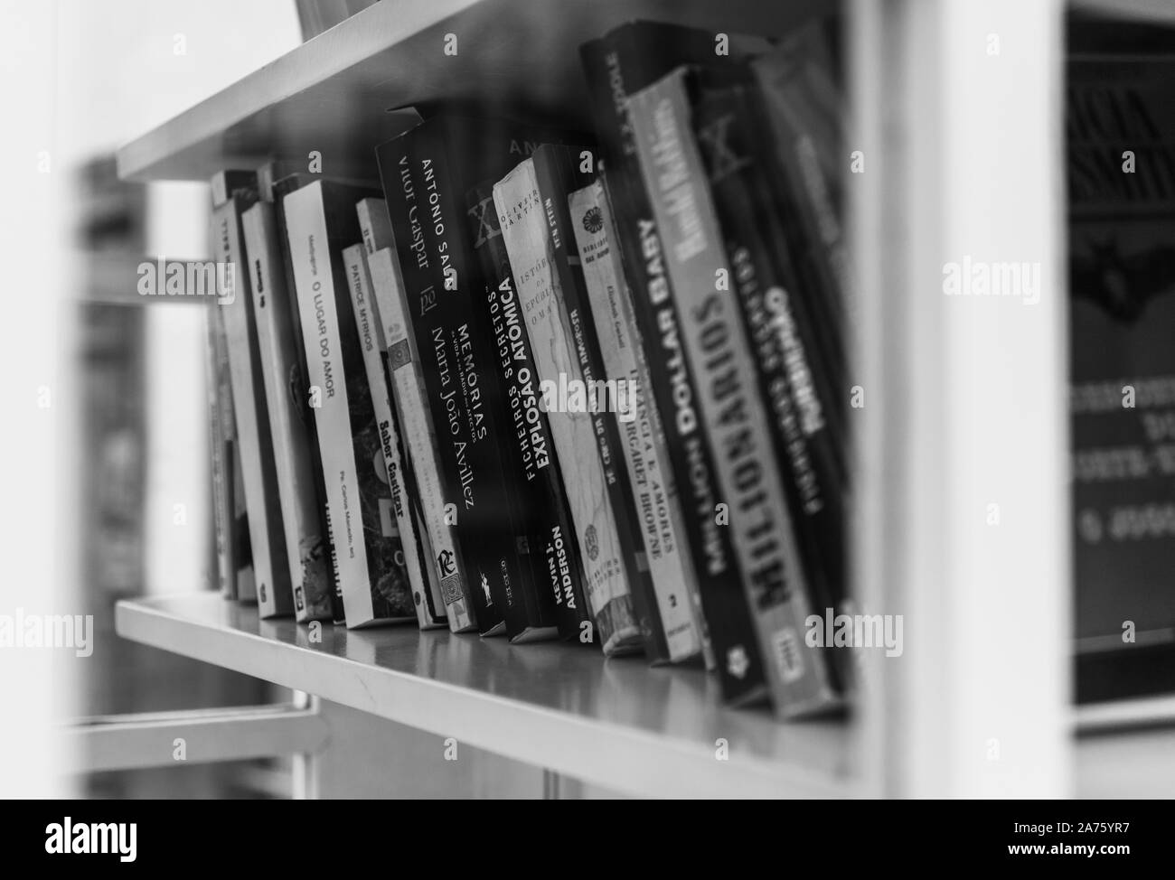 A black and white picture of a group of books sitting on a shelf inside a phone booth. Stock Photo