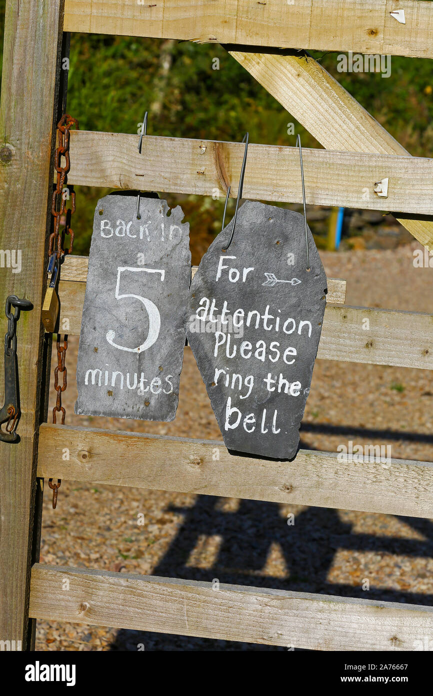A sign painted on slate saying 'back in 5 minutes' and 'for attention please ring the bell' Stock Photo