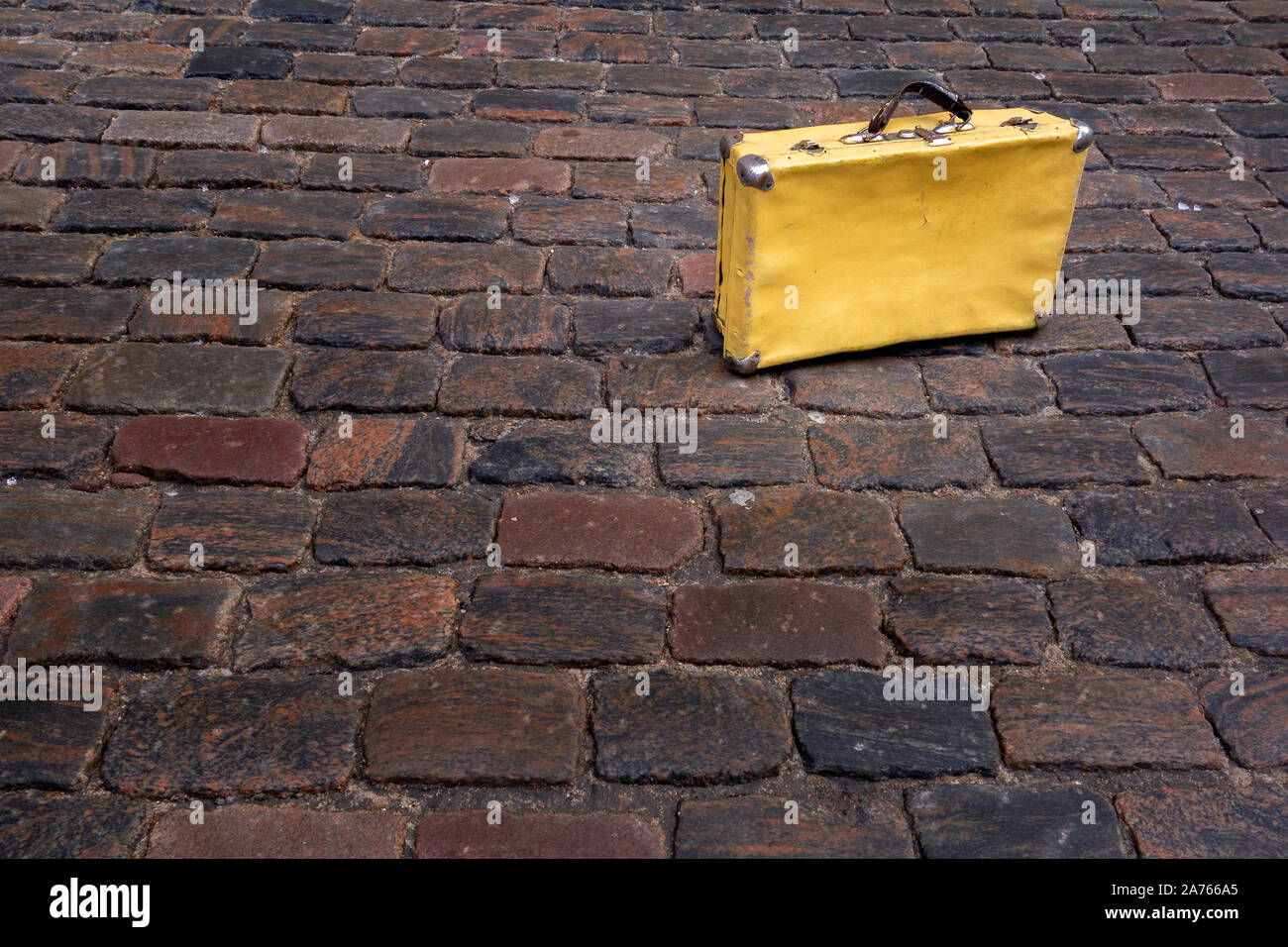 battered yellow suitcase on cobbled street Stock Photo Alamy