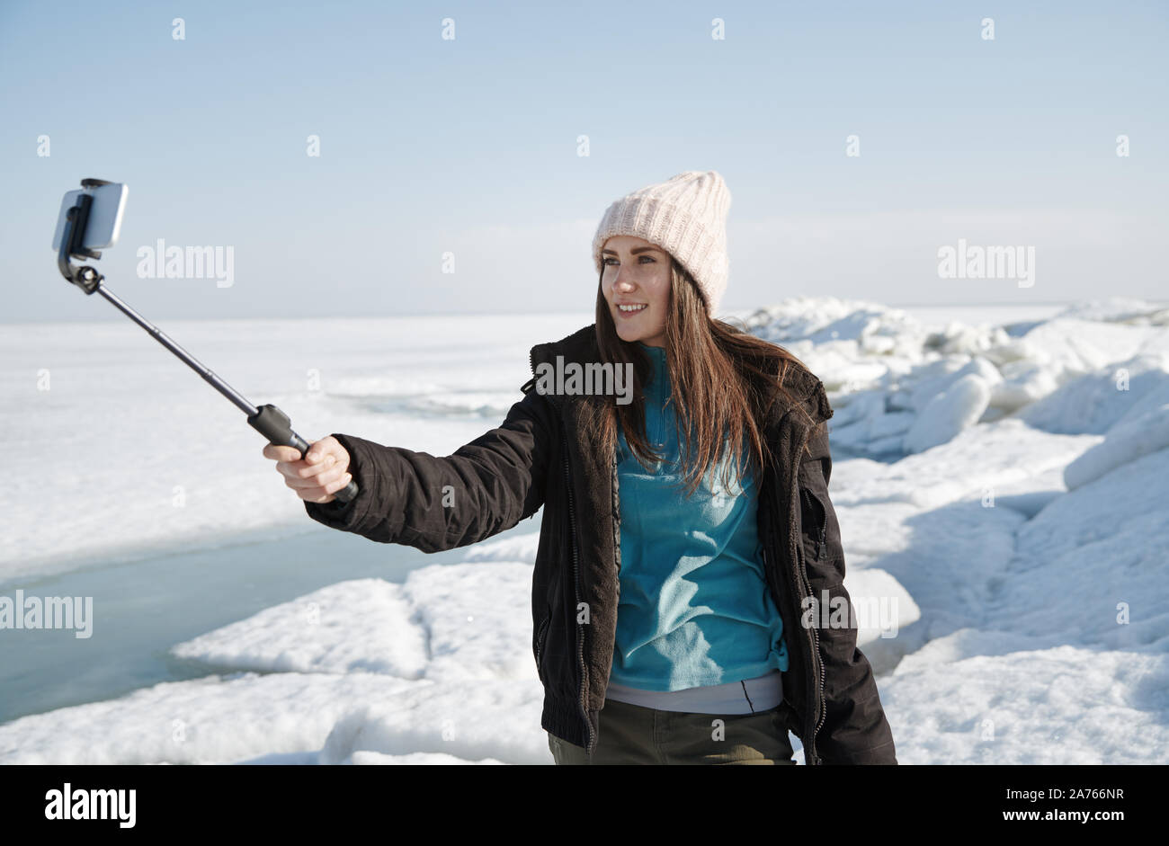 Female traveler at Jokulsarlon Glacial Lagoon using monopod to make selfie picture Stock Photo