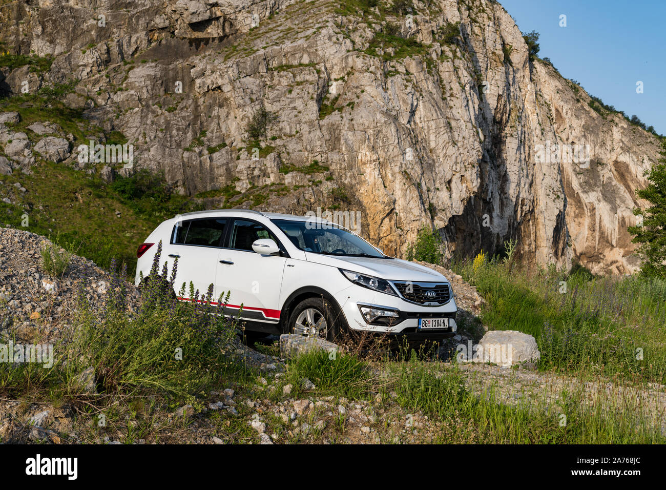 Car Kia Sportage 2.0 CRDI awd or 4x4, white color, on the path the top of the rocky mountain, narrow passage between two large stones. Stock Photo