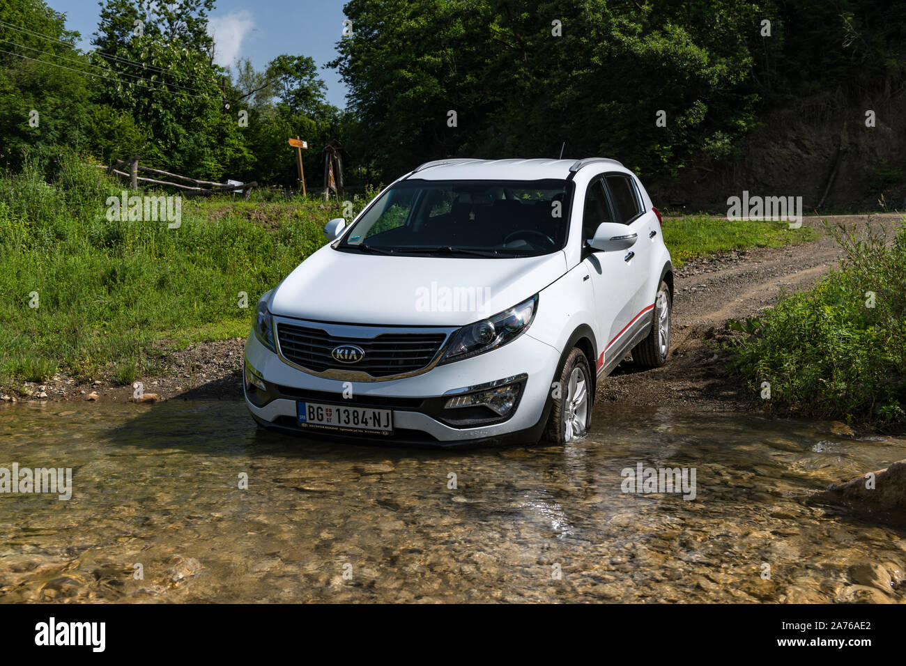 Kia Sportage 2.0 CRDI awd or 4x4, white color, crosses the stream ( creeks ), with a very steep approach, and slippery rocks below. SUV car in water Stock Photo