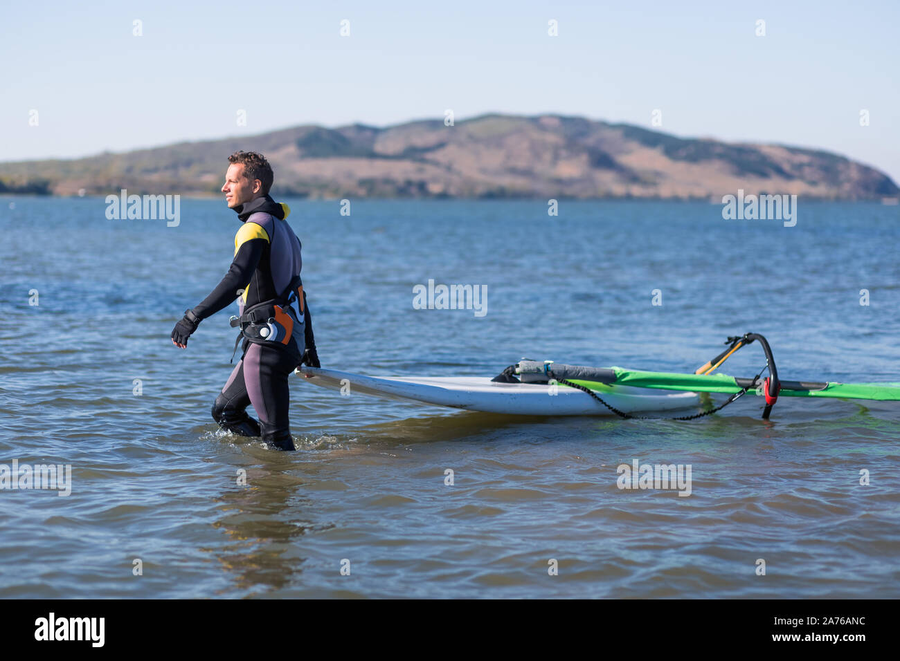 Side view of windsurfer with surfing board and sail coming out from