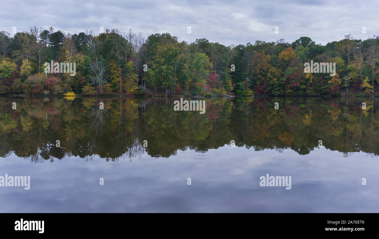 A scenic autumn view of colorful forest foliage reflecting on a lake ...