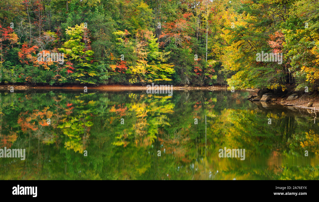 A scenic autumn view of colorful forest foliage reflecting on a lake ...