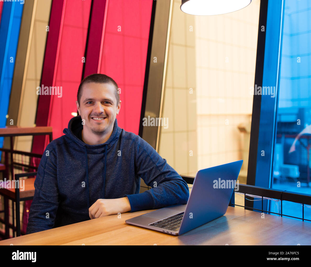 Smiling adult man freelancer sitting at desk with gray laptop Stock Photo