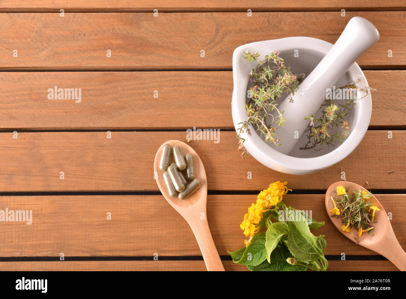 Homemade elaboration of natural medicines with capsules and mortar with plants on wooden table. Alternative natural medicine concept. Top view. Horizo Stock Photo