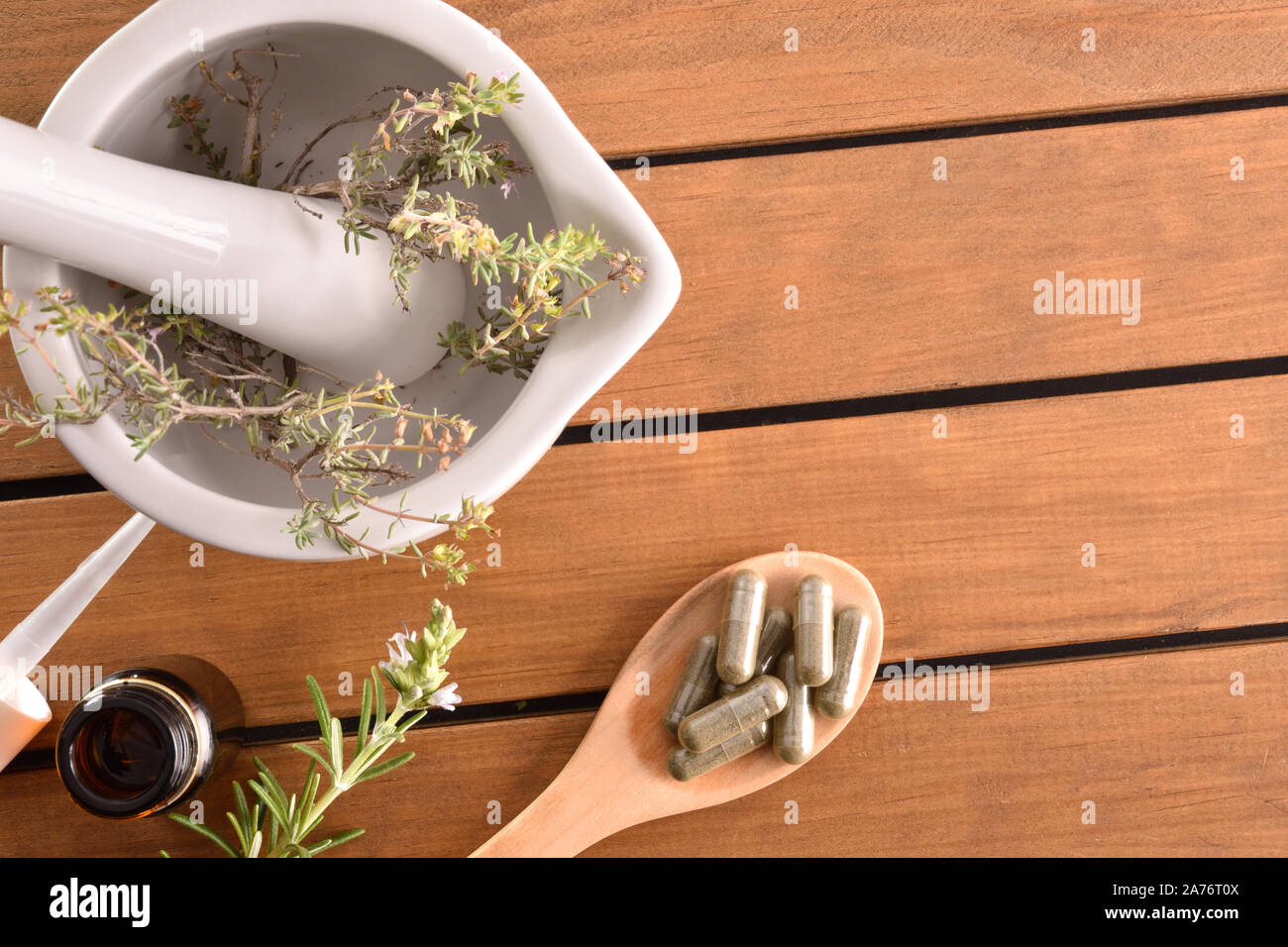 Homemade elaboration of natural medicines with capsules and mortar with plants on wooden table. Alternative natural medicine concept. Top view. Horizo Stock Photo