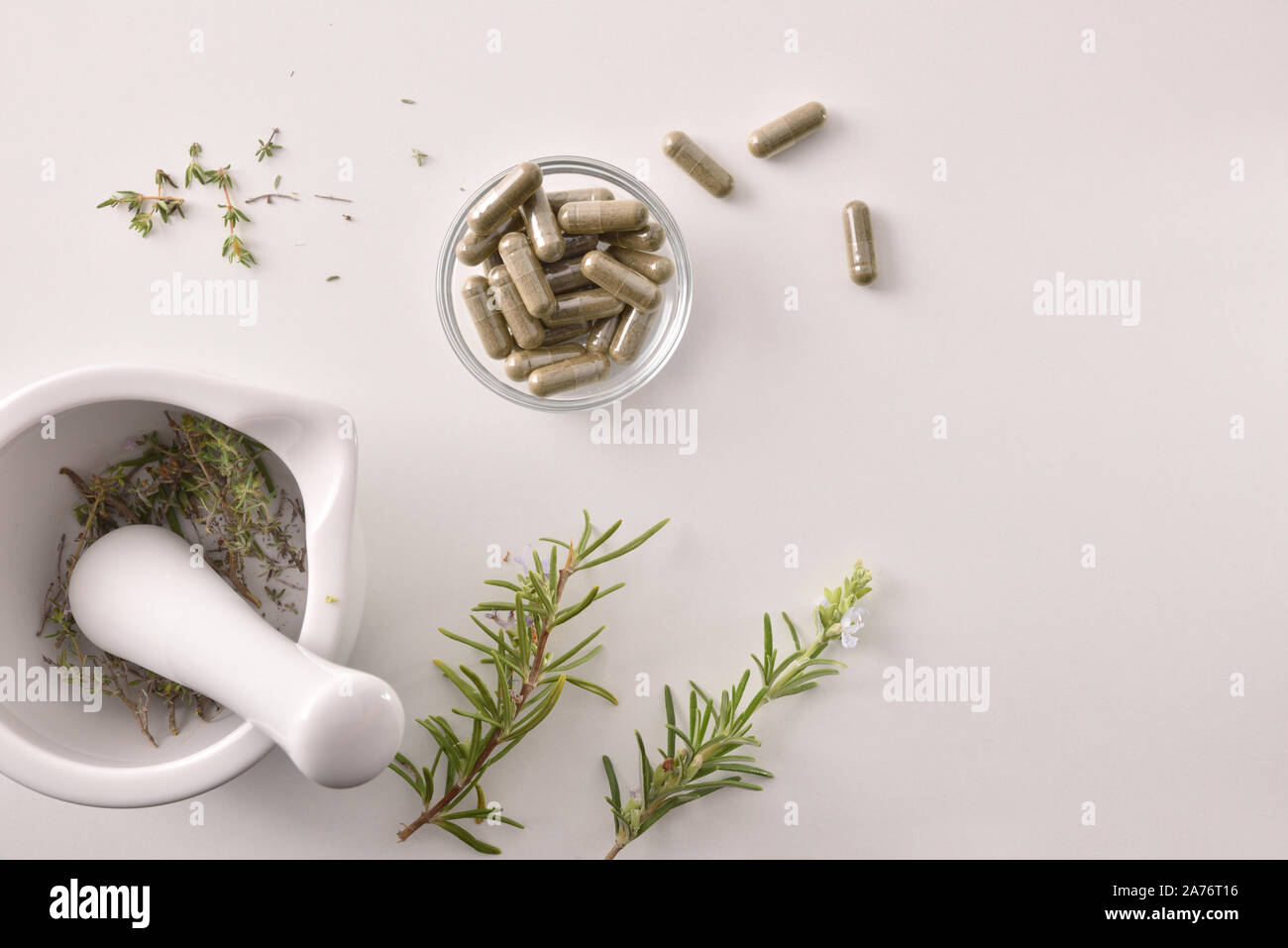 Mortar with herbs for processing natural capsules on white table. Alternative natural medicine concept. Top view. Horizontal composition. Stock Photo