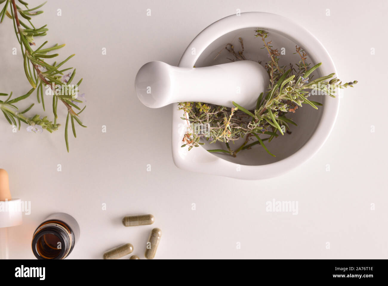 Mortar with herbs for processing natural capsules on white table. Alternative natural medicine concept. Top view. Horizontal composition. Stock Photo