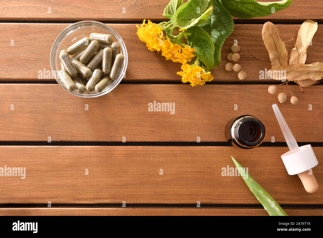 Natural medicine capsules of herbs on wooden table with glass container with plant capsules and dropper bottle with medicinal liquid. Alternative natu Stock Photo