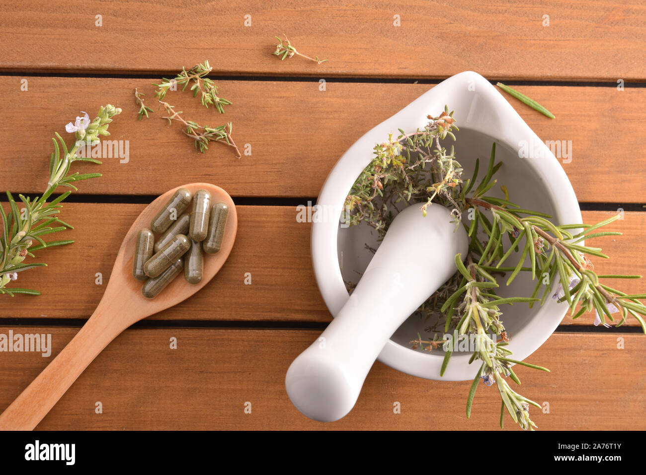 Mortar with herbs for processing natural capsules on wooden spoon on table. Alternative natural medicine concept. Top view. Horizontal composition. Stock Photo