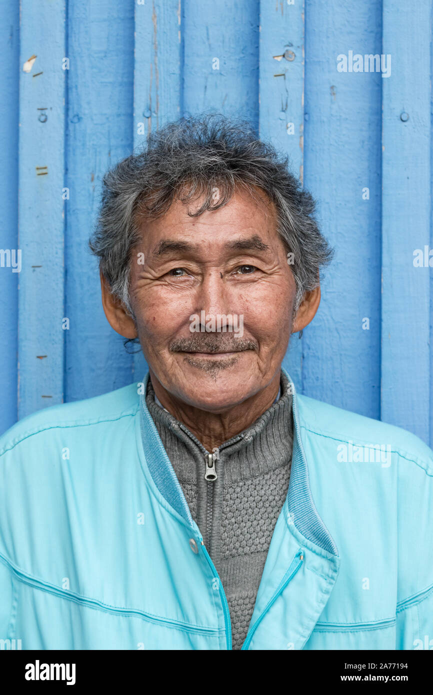 Portrait of an Inuit local mature man looking camera over a striped pattern wall outdoors in Nuuk. Stock Photo