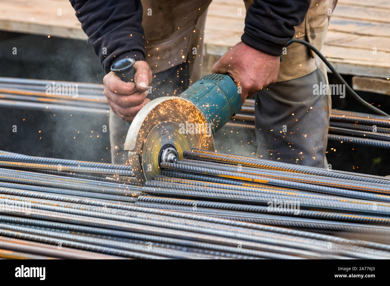 Male hands cutting steel bars with a circular electric grinder Stock