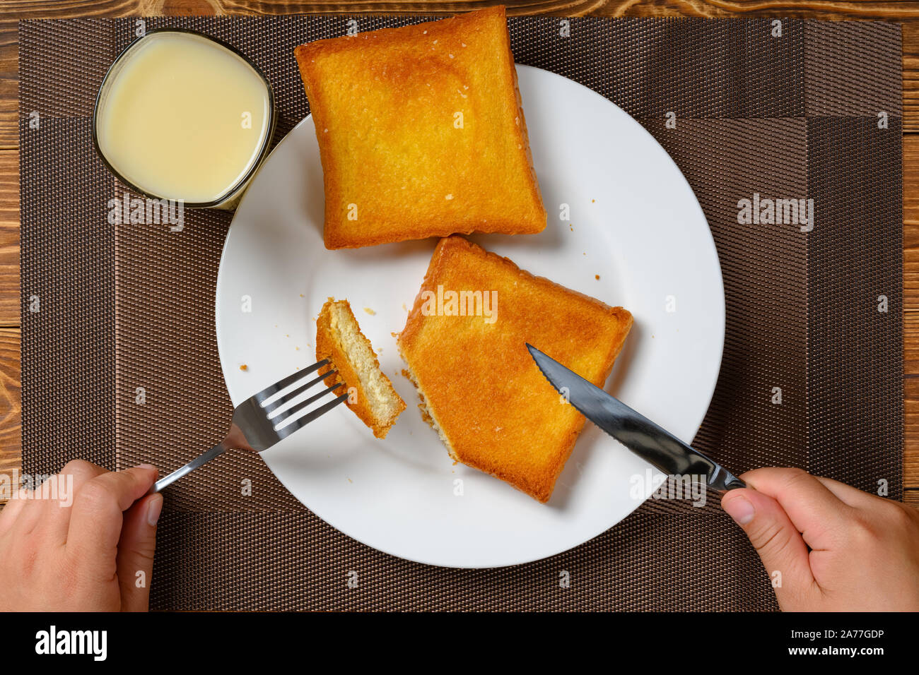 top view man eating toast with fork and knife and cup of soy milk