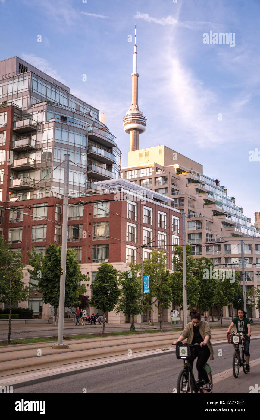 Toronto, Ontario, Canada - 2019 06 09: Torontonians take advantage of a bike share program cycling along Queens Quay in front of residential high rise Stock Photo