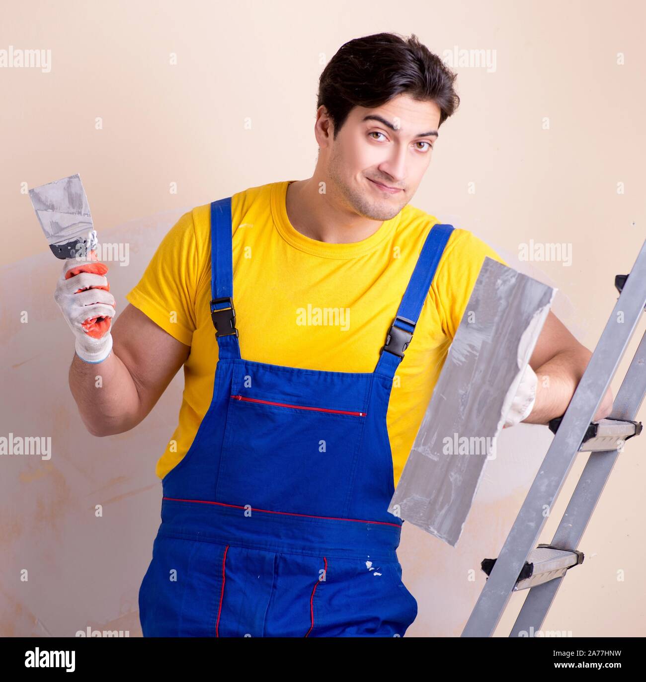 The young contractor employee applying plaster on wall Stock Photo
