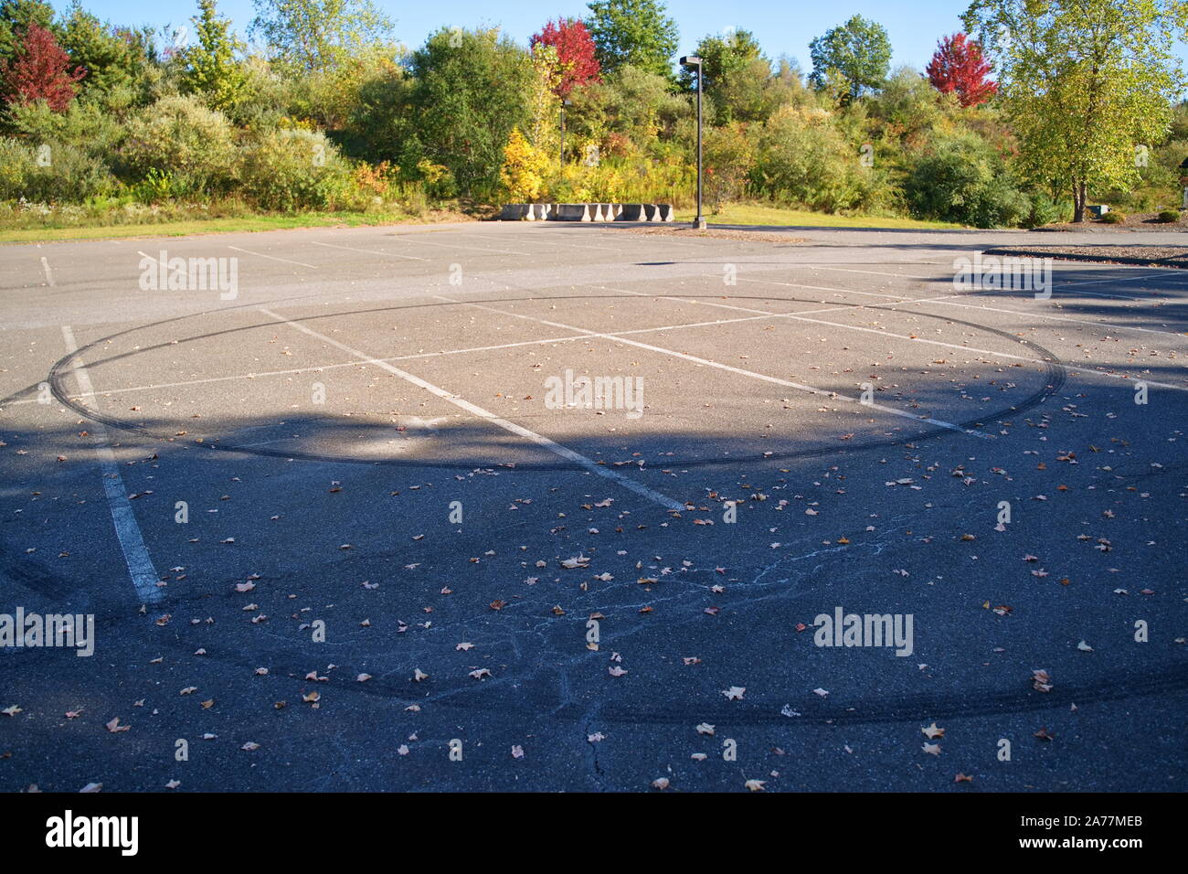 Circular skid marks on an empty parking lot is evident of young people recklessly doing donuts with their cars. Stock Photo
