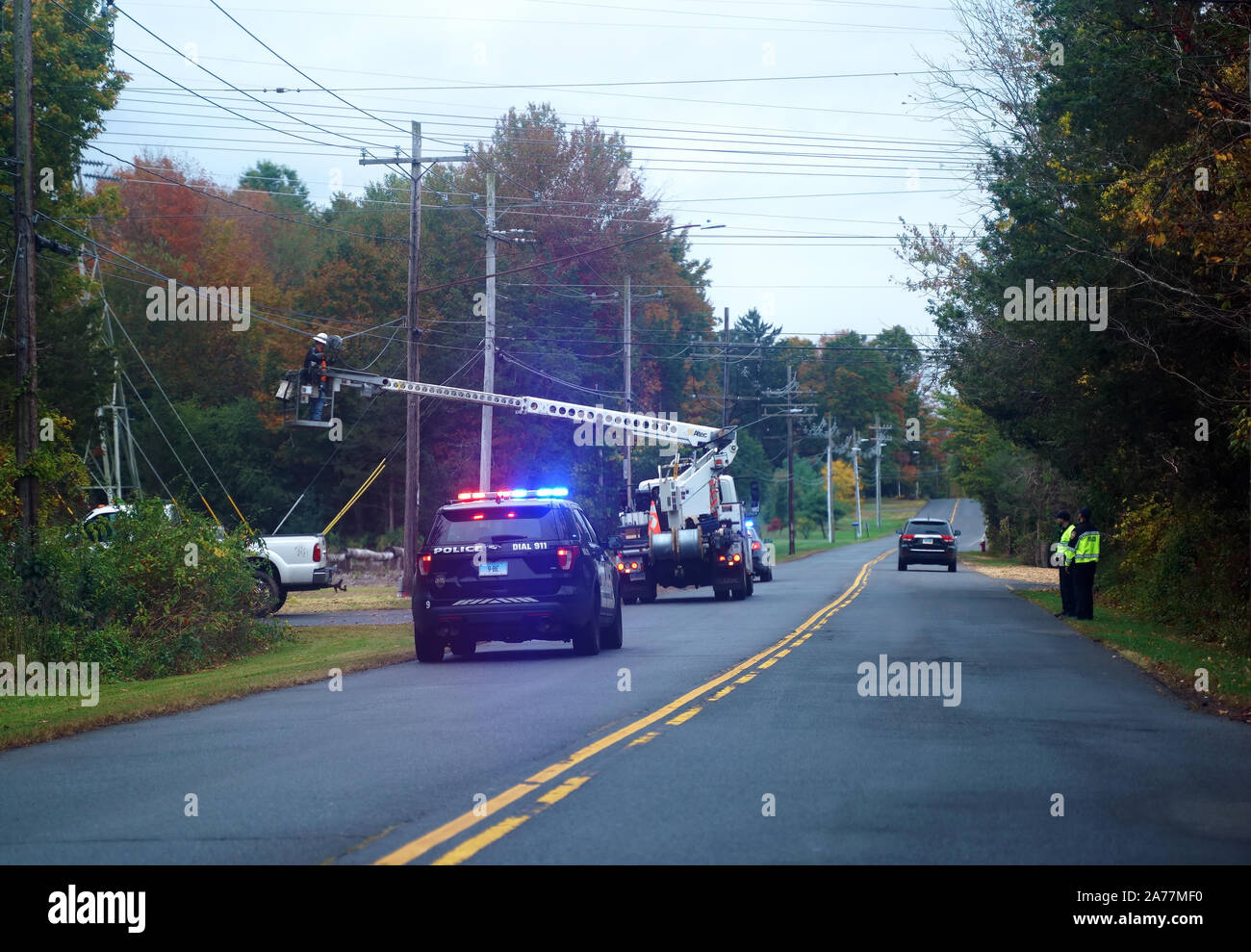 Berlin, CT USA. Oct 3 2019. Police vehicle accompanying telecommunications personnel in hydraulic man lift installing new cable lines. Stock Photo