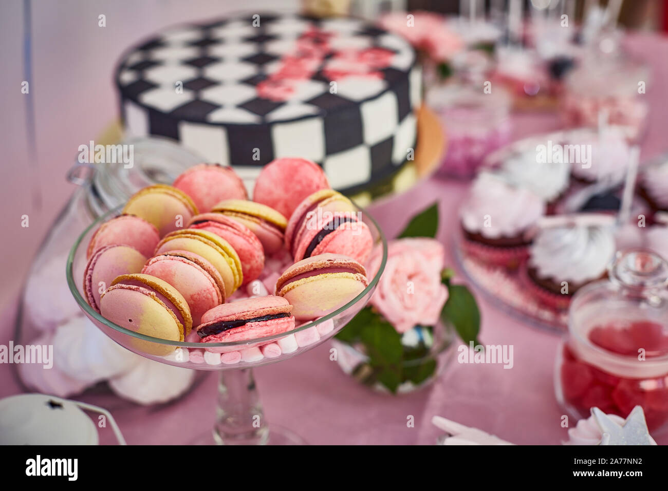 Candy bar with macaroons, cake pops, sweet cake, cookies on brilliant pink table for birthday party Stock Photo