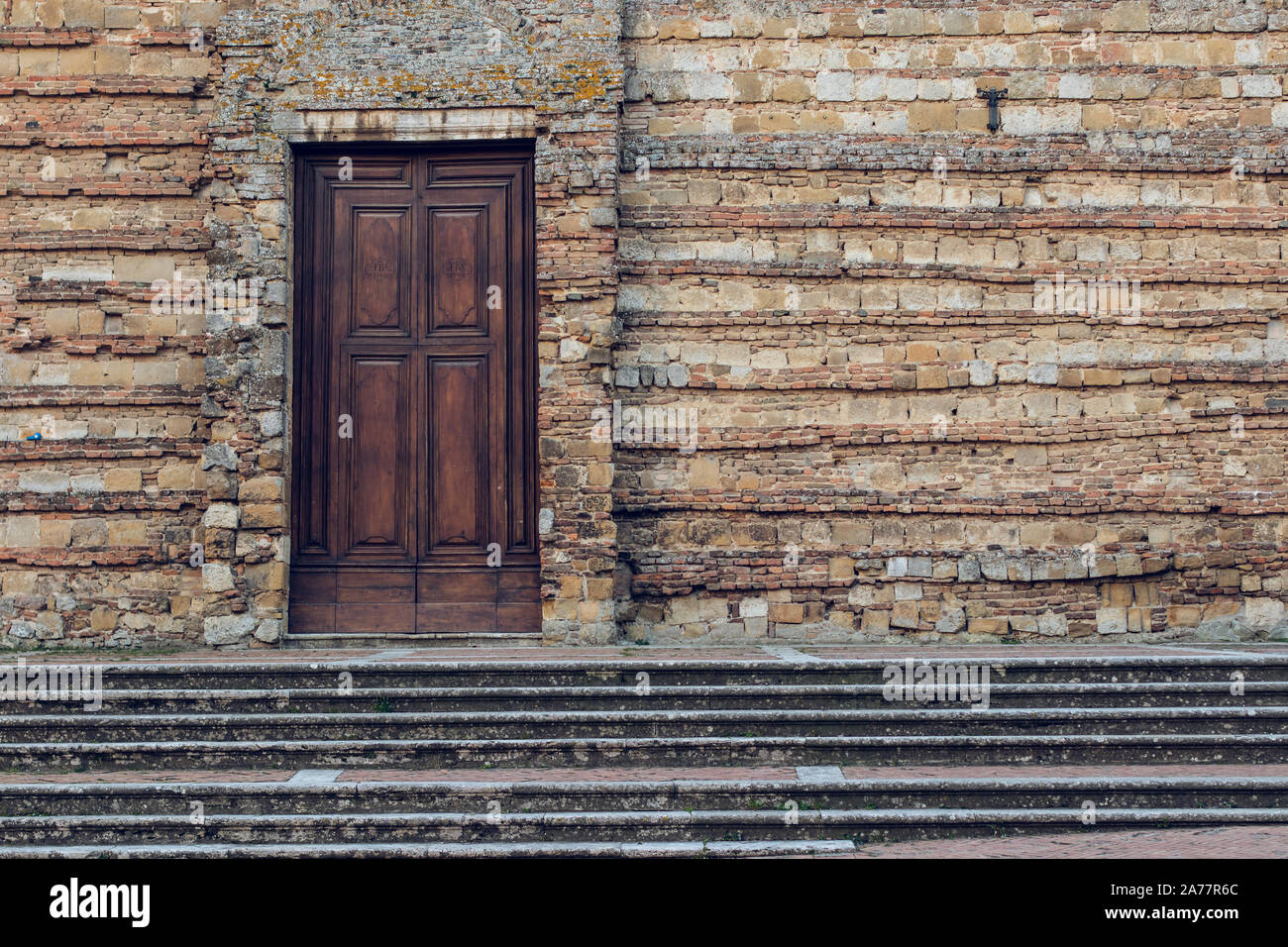 Old wooden closed door on a brick wall facade in Italy Stock Photo