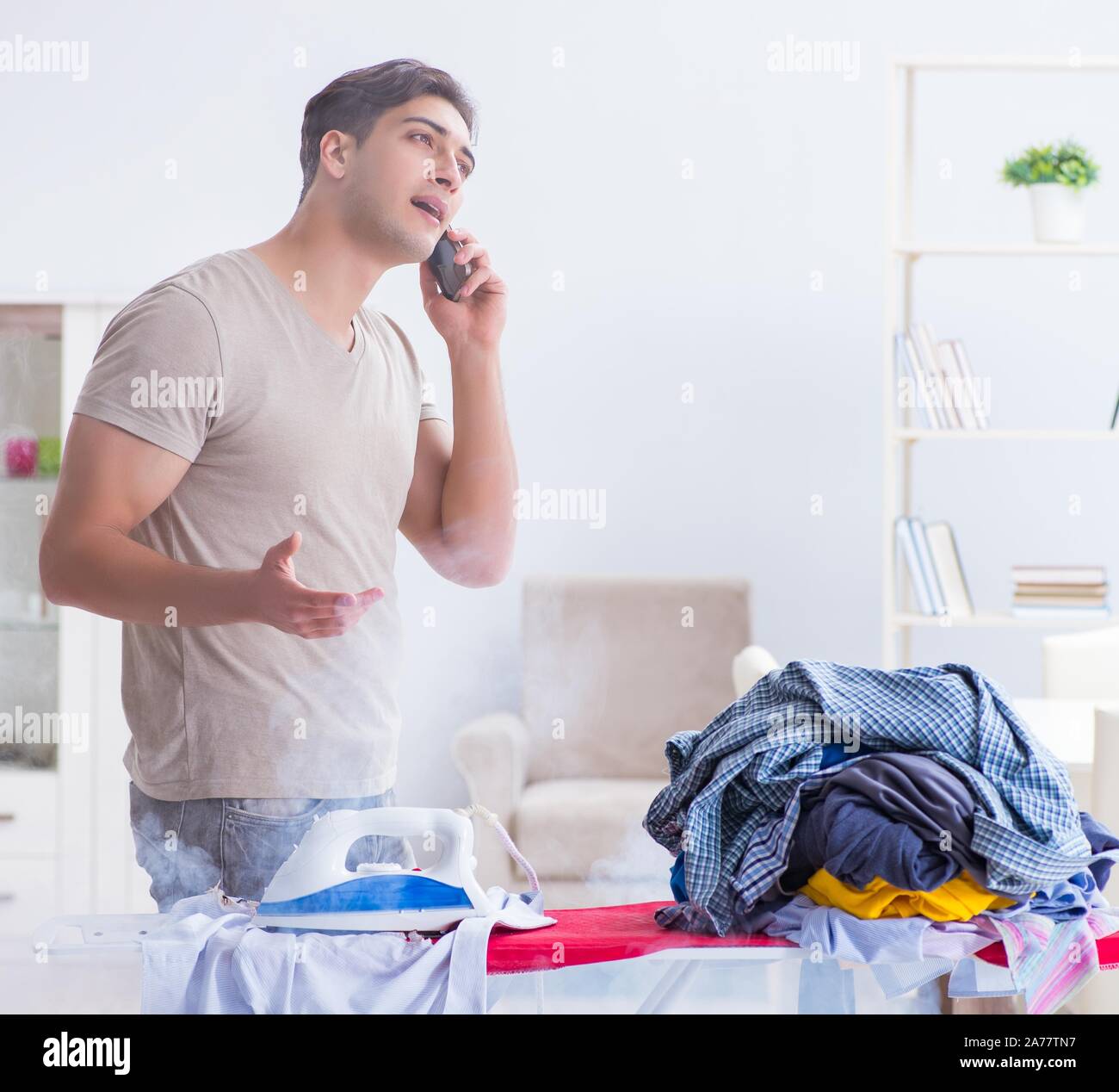 Inattentive husband burning clothing while ironing Stock Photo