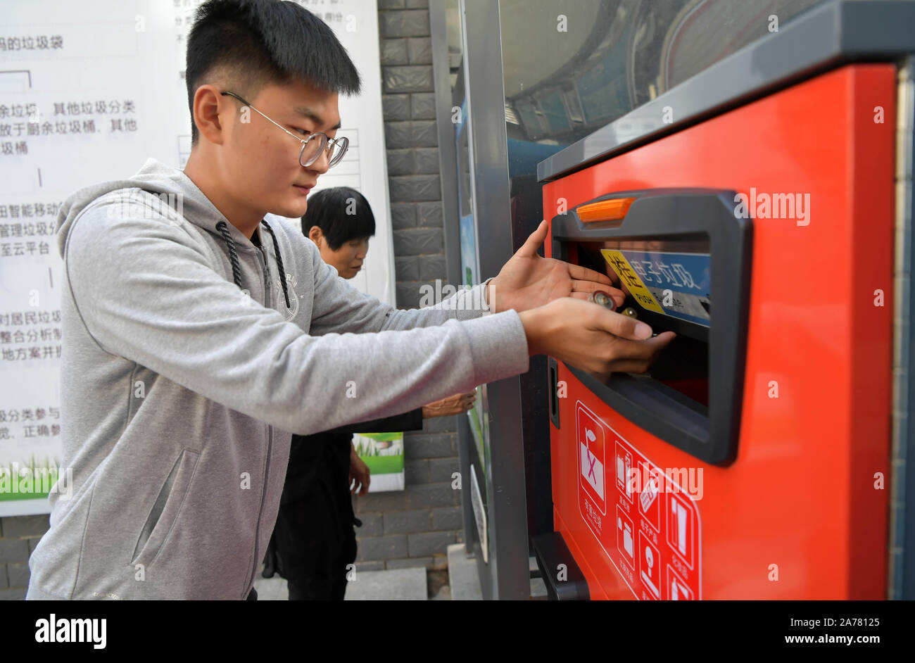 Nanchang, China's Jiangxi Province. 30th Oct, 2019. Residents throw dry cells into a garbage sorting facility in Nanchang County of Nanchang City, east China's Jiangxi Province, Oct. 30, 2019. Nanchang County has been striving to promote garbage sorting by deploying recycling facilities, raising residents' awareness of waste classification and encouraging people to redeem commodities with points earned from garbage sorting since 2018. Credit: Peng Zhaozhi/Xinhua/Alamy Live News Stock Photo