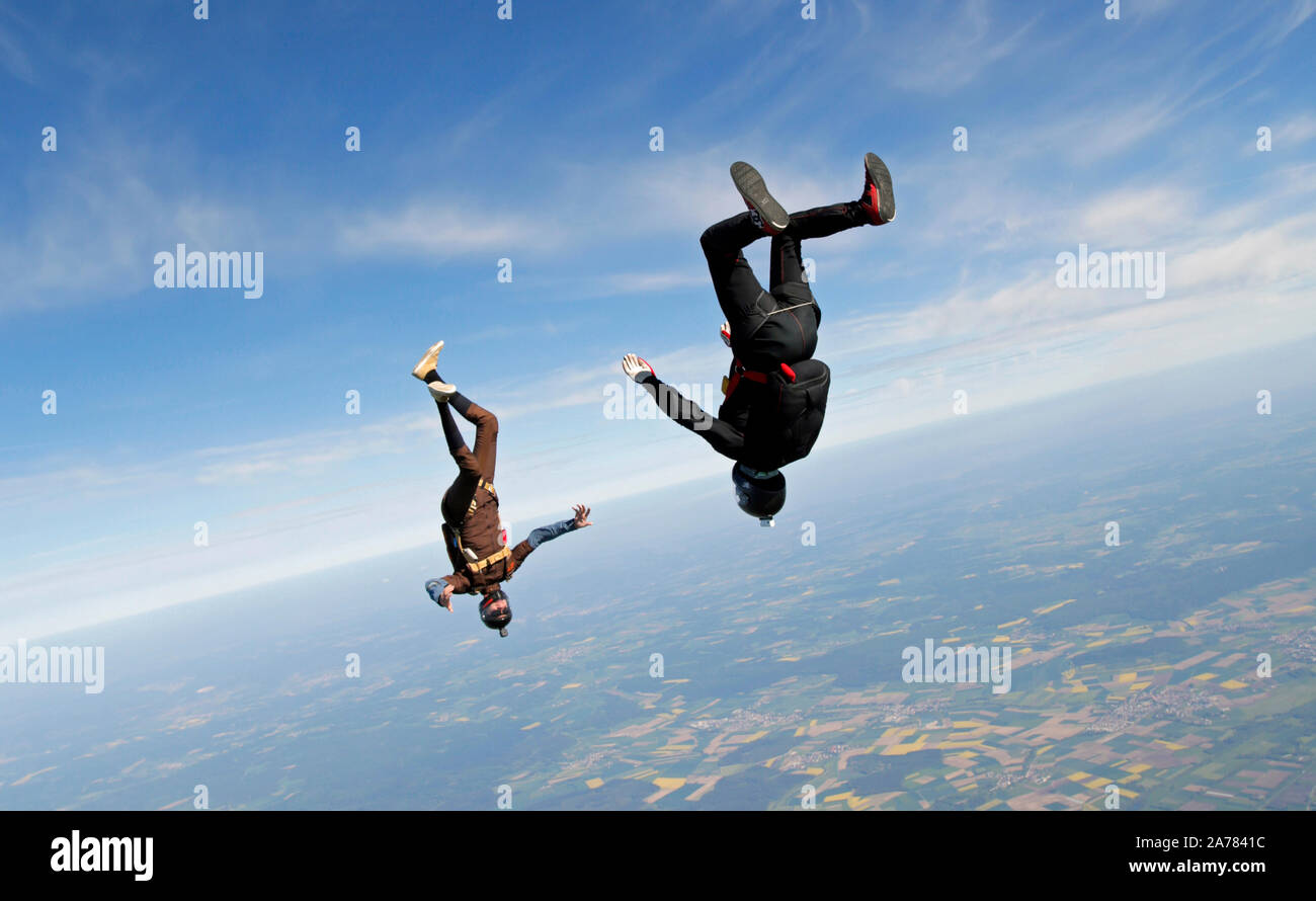 This skydiving team is flying in a head down position in the blue sky and having fun. Soon they will hold grips together and form a star formation. Stock Photo