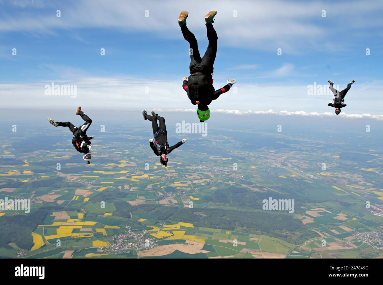Four skydivers are trying to fly togehter in a formation with a speed of over 120mph. However they are tracking around each other and having fun! Stock Photo