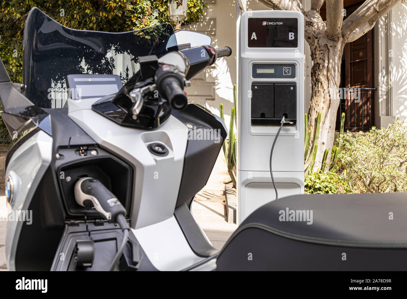 BMW C Evolution electric scooter, motorcycle, plugged in to a Circutor charging point on a street in Santa Cruz de Tenerife, Canary Islands, Spain Stock Photo