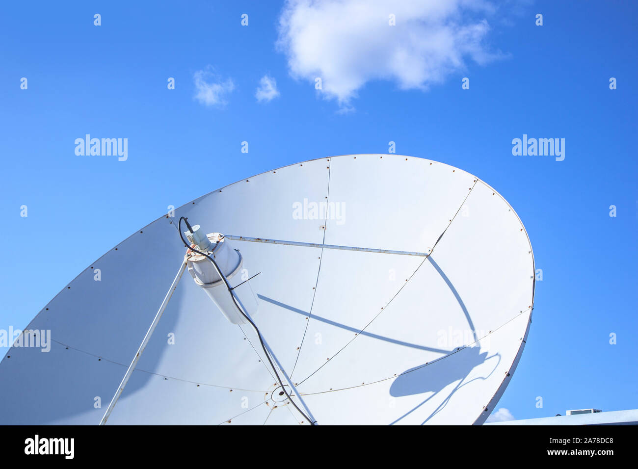 Big parabolic satellite antenna for telecommunications on a background of blue sky. Stock Photo