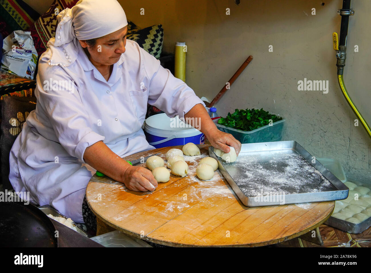 Female chef kneading dough to make flat bread snack called Gozleme in restaurant window, Istanbul, Turkey. Stock Photo