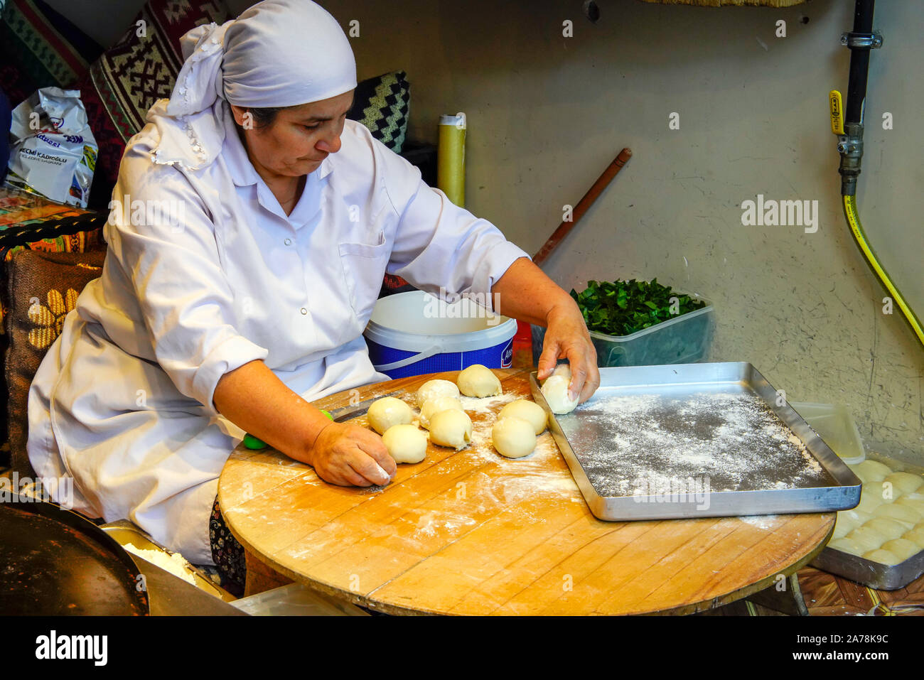 Female chef kneading dough to make flat bread snack called Gozleme in restaurant window, Istanbul, Turkey. Stock Photo