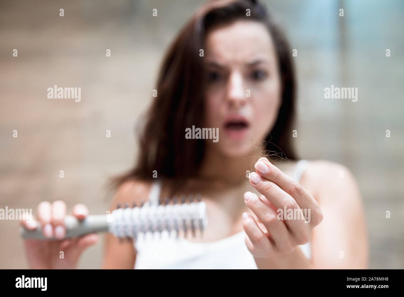brunette woman looking frightened when sees a lot of fallen hair on the brush hair loss problem Stock Photo