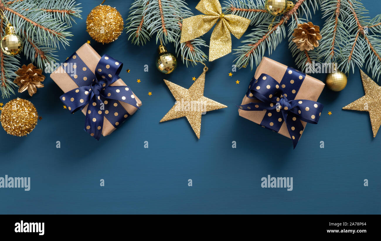 Wide arch shaped Christmas border on blue background, composed of Xmas tree fir branches and ornaments in golden and blue. Flat lay, top view, overhea Stock Photo