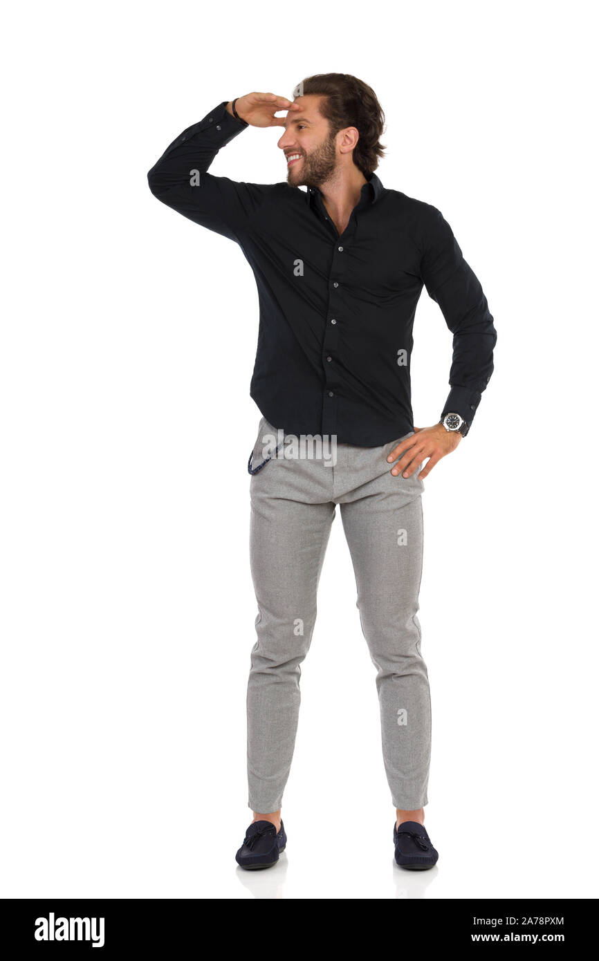 Happy handsome man in moccasins gray trousers and black shirt is