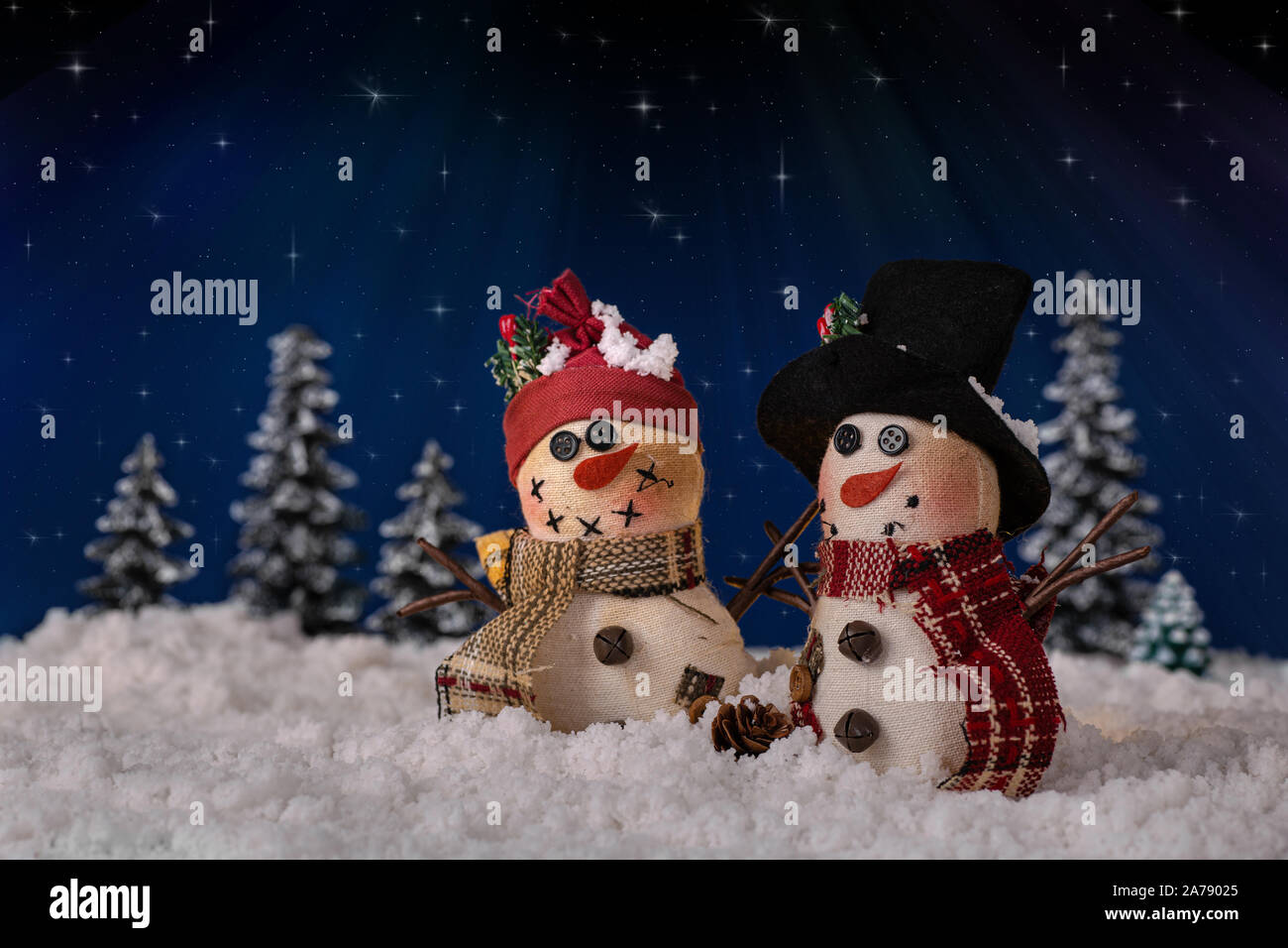 Holiday snowmen figurines on snowy surface against a night sky background with shining stars Stock Photo