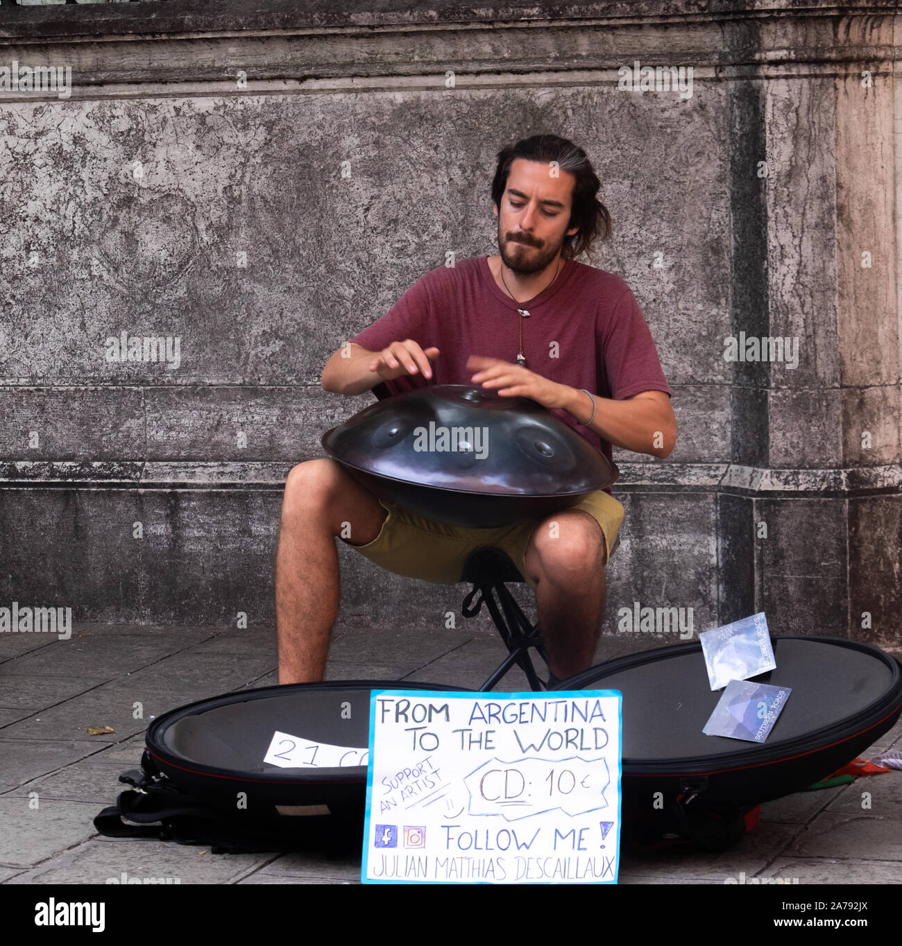 Single male busker playing an unusual upturned steel lid with dents like a  steel drum. Sitting on a stool on a Venetian street for the tourists Stock Photo