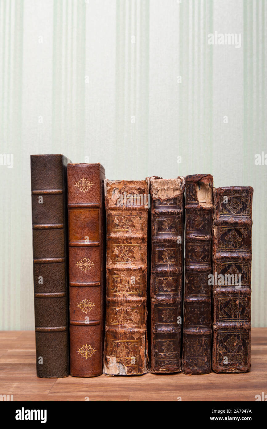 Antique books stand on the wooden table or wooden shelf. Green background, wallpaper. Stock Photo