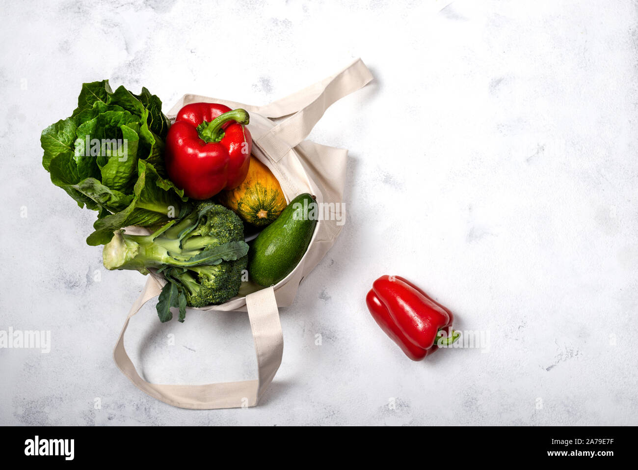 Fabric eco bag full of different fresh vegetables on a light background ...