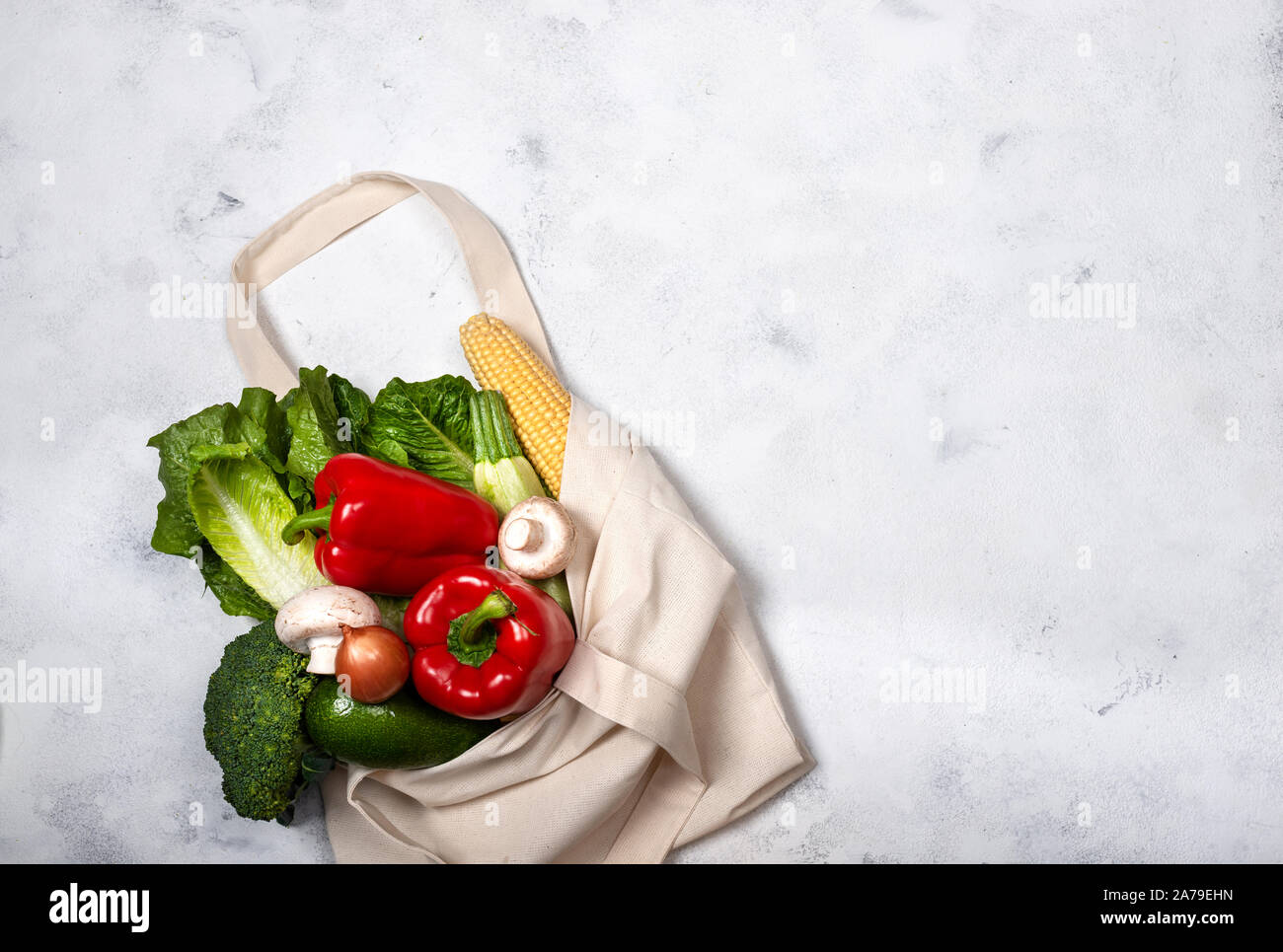 Grocery fabric eco bag with different fresh vegetables on a light ...
