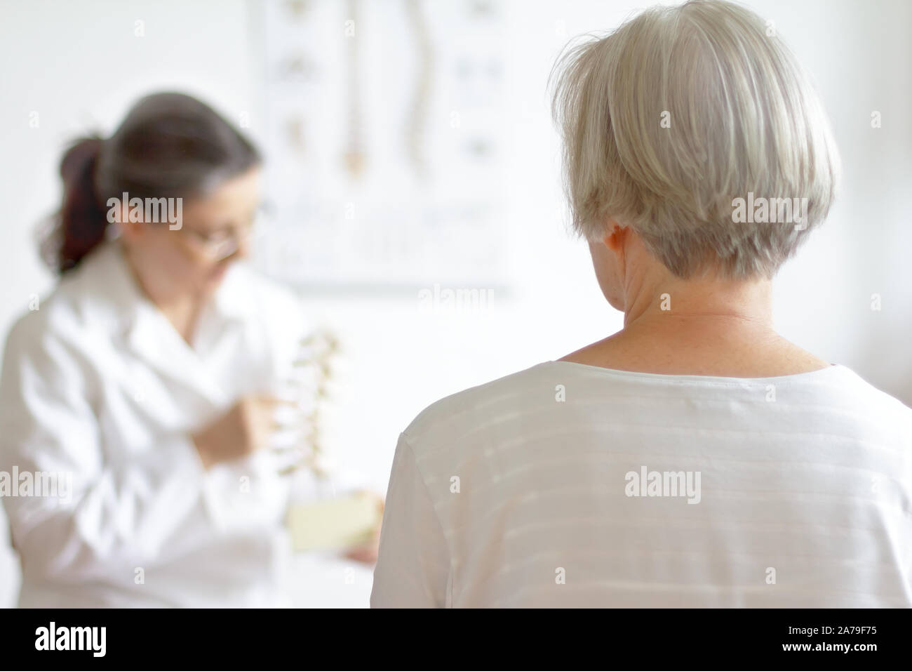 Aging and back pain concept: senior patient consulting her physician because of herniated disk. Stock Photo
