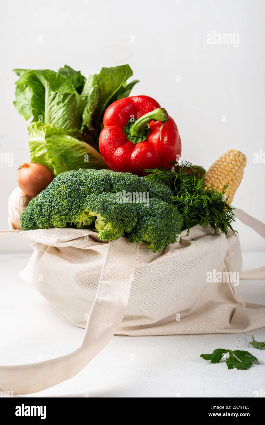 Fabric eco bag full of different fresh vegetables on a light background ...