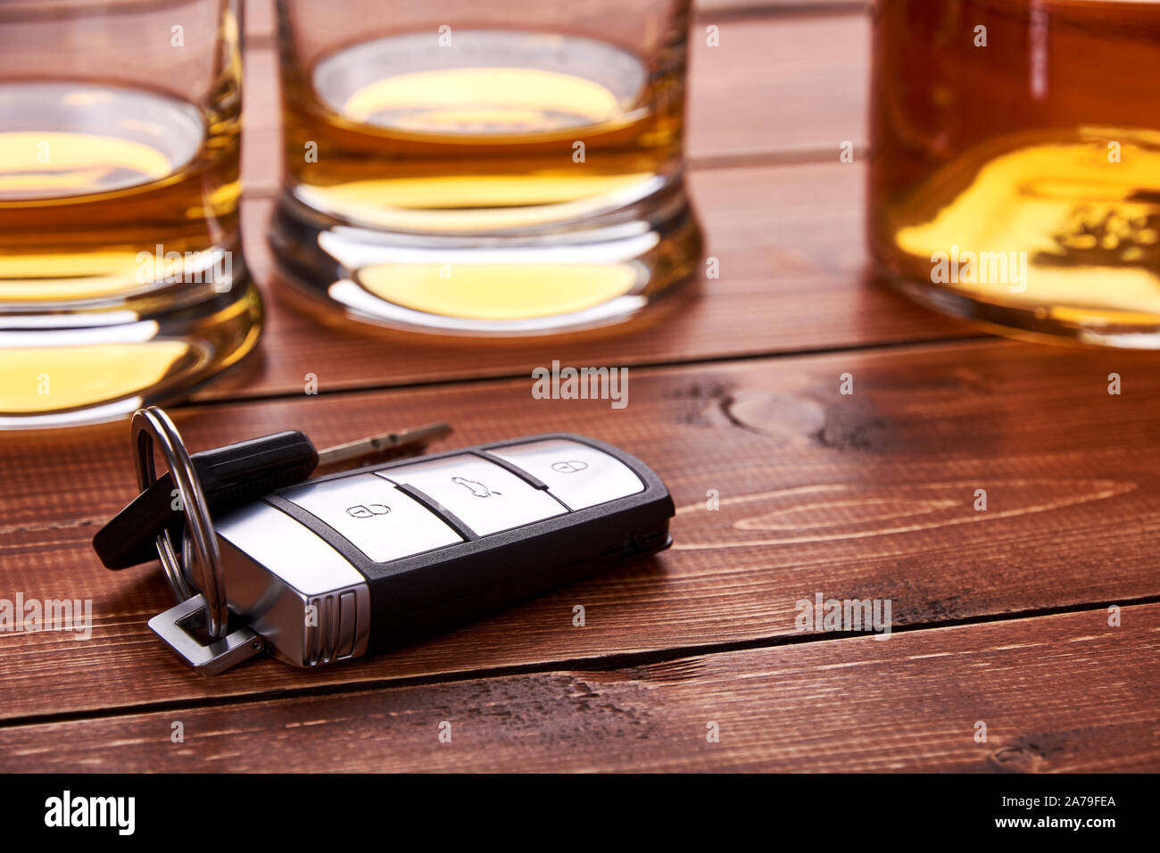 Still life on old wooden table top. Car keys, several glasses and a bottle of whiskey or alcohol. Suitable for drunk driving. Stock Photo