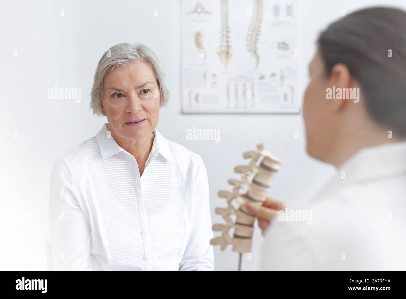 Aging and back pain concept: doctor of rheumatolgy showing her senior ...