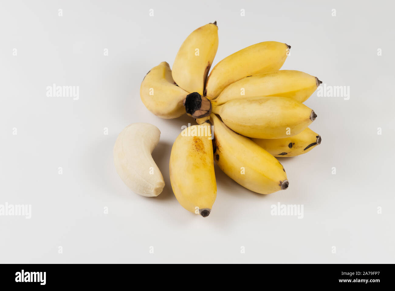 Small ripe bananas in a bunch Caribbean lady fingers exotic yellow white background Stock Photo