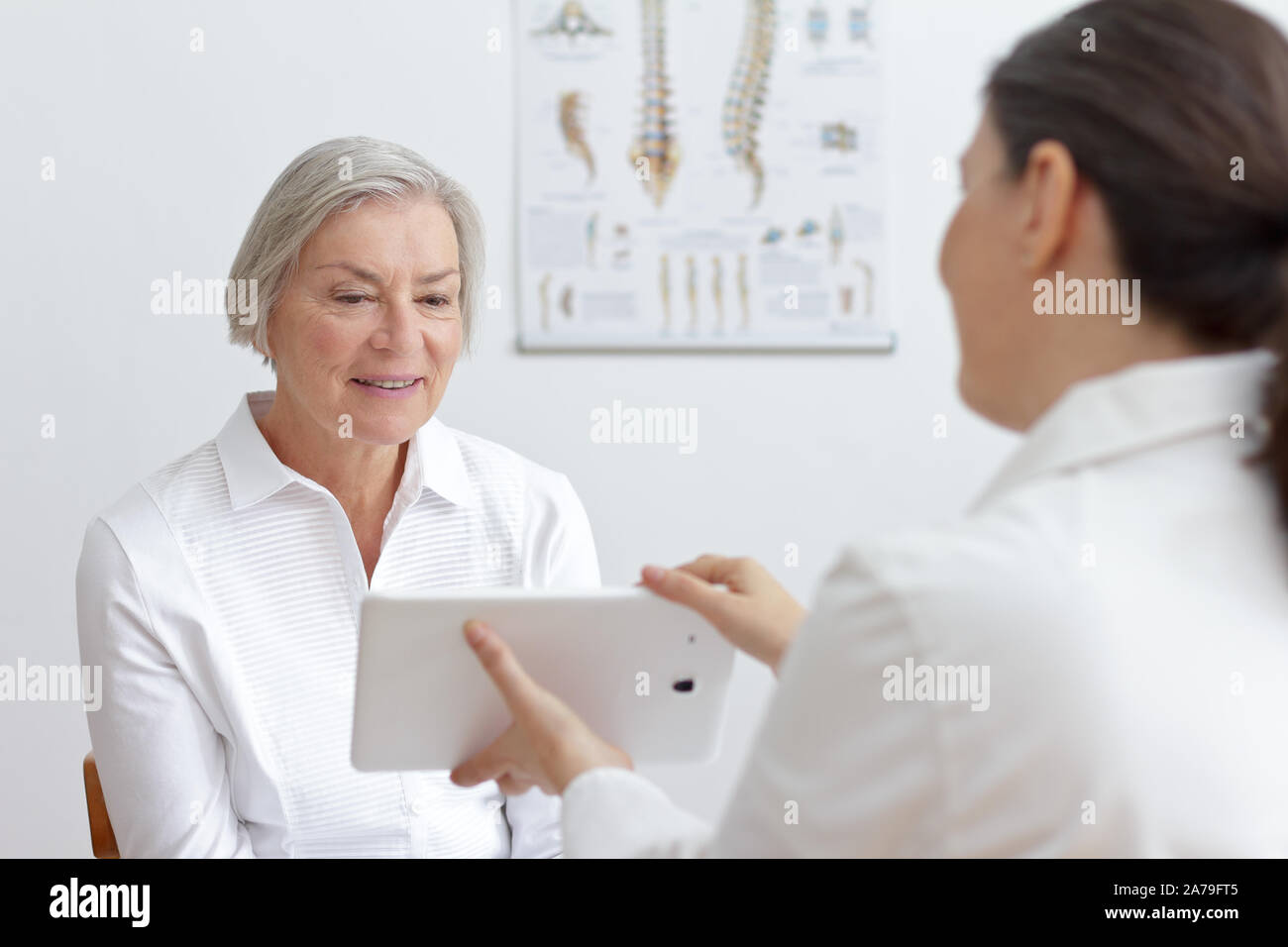 Health care technology concept: general practitioner showing her smiling senior patient lab results on a tablet pc. Stock Photo
